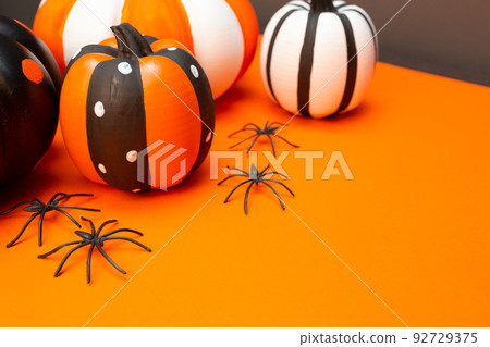 Halloween. Black spiders, four pumpkins in different colors and sizes. Place for text. Copy space. Orange background. Preparation for the Halloween holiday. Halloween. Black spiders, four pumpkins in different colors and sizes. Place for text. Copy space. Orange background. Preparation for the Halloween holiday. 92729375
