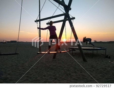 日落海灘上的衝浪板鞦韆和蹦床（荷蘭席凡寧根） 92729517
