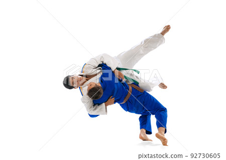 Studio shot of two men, professional judo athletes training isolated over white background. Throwing exercises 92730605