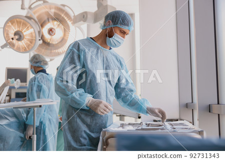 Professional doctor surgeon takes scalpel before surgery in operation room at the hospital Professional doctor surgeon takes scalpel before surgery in operation room at the hospital 92731343