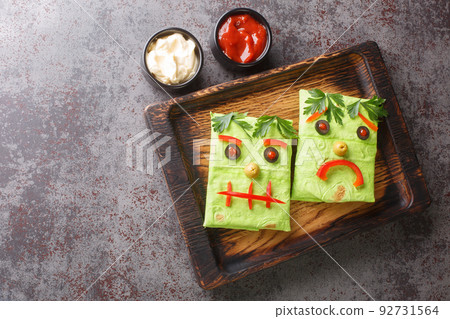 Halloween Monster Wraps burrito sandwich with funny face on a wooden tray. horizontal top view Halloween Monster Wraps burrito sandwich with funny face on a wooden tray. horizontal top view 92731564