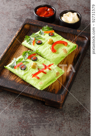 Funny kids burrito monster with sauces on a wooden tray. halloween food. vertical 92731579
