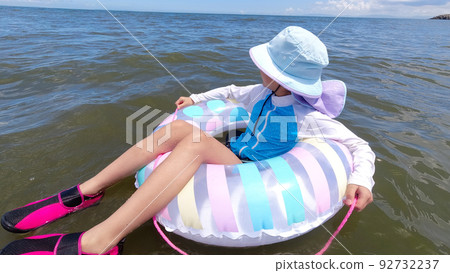 A cute elementary school girl playing at the beach in summer 92732237