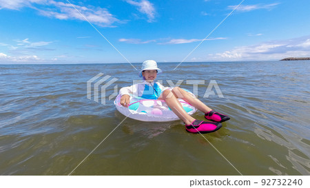 A cute elementary school girl playing at the beach in summer A cute elementary school girl playing at the beach in summer 92732240