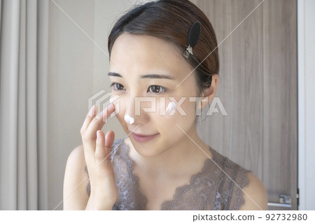 Woman applying moisturizing cream on her face Woman applying moisturizing cream on her face 92732980