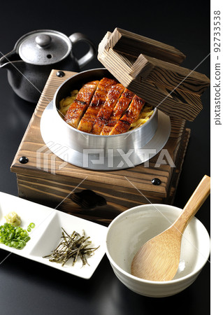 Kamameshi with eel kabayaki and dashi chazuke set against a black background 92733538
