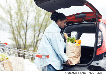 Young Woman Putting Groceries in Car 92735603