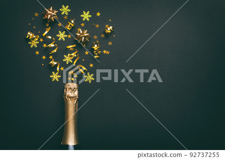 Creative flat lay composition with bottle of champagne and space for text on color background. Champagne bottle with colorful party streamers. holiday or christmas concept Creative flat lay composition with bottle of champagne and space for text on color background. Champagne bottle with colorful party streamers. holiday or christmas concept 92737255