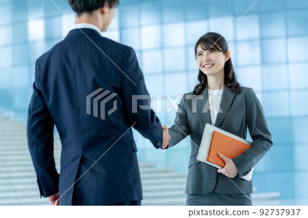 Businessman and businesswoman in suits shaking hands 92737937