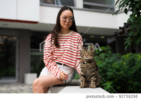 Young woman and tabby cat sitting on a bench outdoors. Young woman and tabby cat sitting on a bench outdoors. 92738298