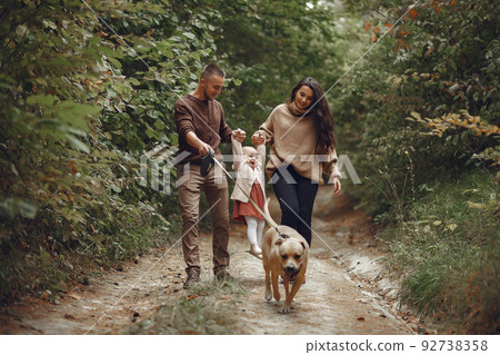 Family with cute little daughter. Father in a brown sweater. Family in a autumn field with dog 92738358
