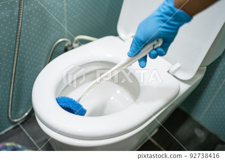Maid cleaning toilet bowl with brush in bathroom at home. Maid cleaning toilet bowl with brush in bathroom at home. 92738416