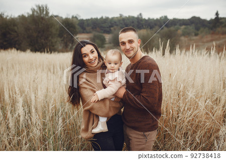 Family with cute little daughter. Father in a brown sweater. Family in a autumn field Family with cute little daughter. Father in a brown sweater. Family in a autumn field 92738418