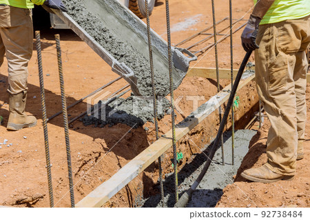 Concrete trenches are poured to form the foundation for a house as a method of constructing a solid wall 92738484