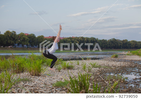 Young woman does yoga on rocks in nature Young woman does yoga on rocks in nature 92739050