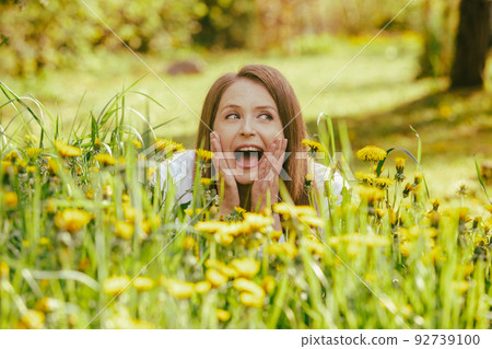 Smiling woman lying at the dandelion field Smiling woman lying at the dandelion field 92739100