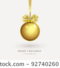 Hanging a golden Christmas ball with a bow 92740260