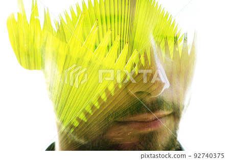 Double exposure portrait of a man combined with an image of a palm leaves 92740375
