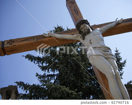 A sculpture of the crucified Jesus Christ against a clear sky. Bottom view. Crucifixion. 92740716