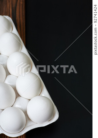 Tray with white chicken eggs on a dark background Tray with white chicken eggs on a dark background 92741424