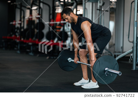 Sporty Black Man Lifting Heavy Barbell While Training At Gym Sporty Black Man Lifting Heavy Barbell While Training At Gym 92741722