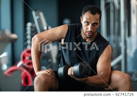 Portrait Of African American Male Athlete Training With Dumbbell At Gym Portrait Of African American Male Athlete Training With Dumbbell At Gym 92741726
