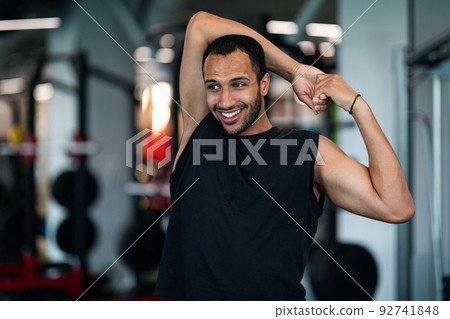 Portrait Of Athletic Black Guy Stretching Arm Muscles At Gym 92741848