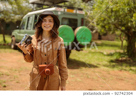 Happy woman on safari using photo camera Happy woman on safari using photo camera 92742304