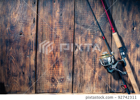 Spinning with a reel on a wooden background. Fishing screensaver with spinning. Spinning and space. Copy Spce. Spinning with a reel on a wooden background. Fishing screensaver with spinning. Spinning and space. Copy Spce. 92742311