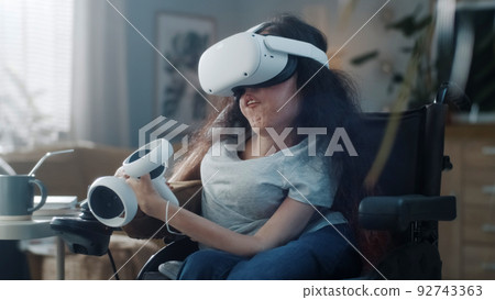 Woman with a disability in VR headset at home Woman with a disability in VR headset at home 92743363