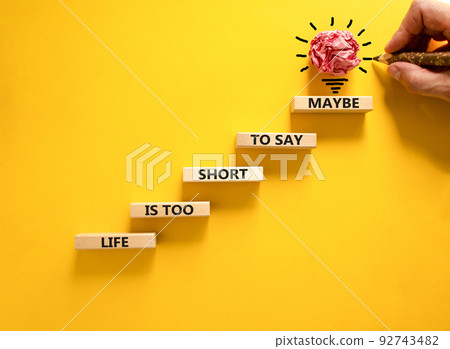 Life is short for maybe symbol. Concept words Life is too short to say maybe on wooden blocks on a beautiful yellow table yellow background. Businessman hand. Business motivational life maybe concept. 92743482