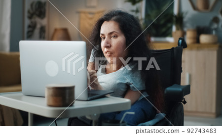 Woman in a wheelchair surfing internet Woman in a wheelchair surfing internet 92743483