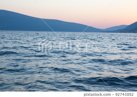 Blue seascape with blue mountains on sunset. A backing with sea and mountains for branding, calendar, postcard, screensaver, wallpaper, poster, banner, cover, website. A place for your design or text 92743892
