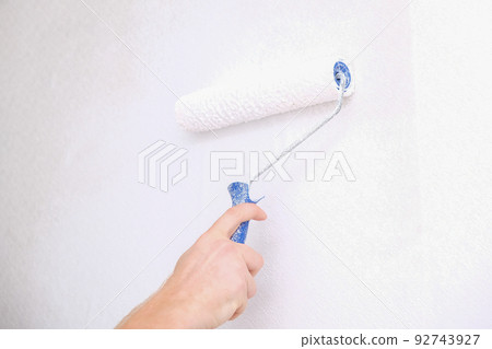 A man is painting vinyl wallpaper with velour A man is painting vinyl wallpaper with velour 92743927
