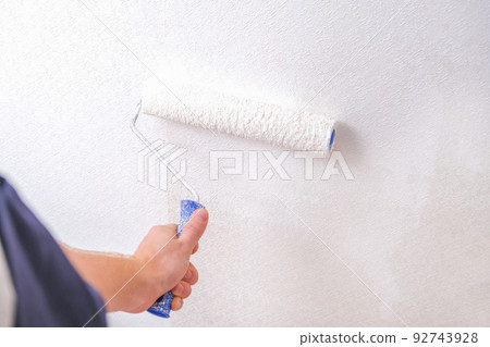 A man is painting vinyl wallpaper with velour A man is painting vinyl wallpaper with velour 92743928