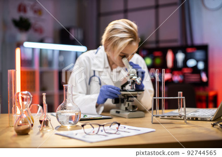 Young female researcher looking at the microscope in the life science. 92744565