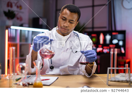 Positive male african scientist or medical in lab coat holding test tube with reagent 92744643