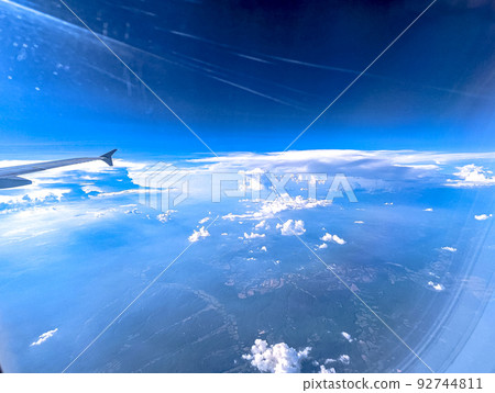 Clouds and sky as seen through window of an aircraft 92744811