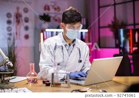 Scientist working with laptop for vaccine development in pharmaceutical laboratory. Scientist working with laptop for vaccine development in pharmaceutical laboratory. 92745061