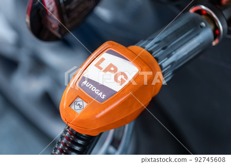 Close-up detail view of fuel autogas pump gun connected with noozle adapter to car tank to refill at car gas filling station. Refueling vehicle with liquefied lpg or lng product. Safety technology 92745608