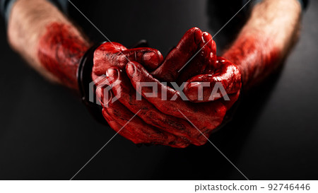 Close-up of male bloody handcuffed hands on a black background. Close-up of male bloody handcuffed hands on a black background. 92746446