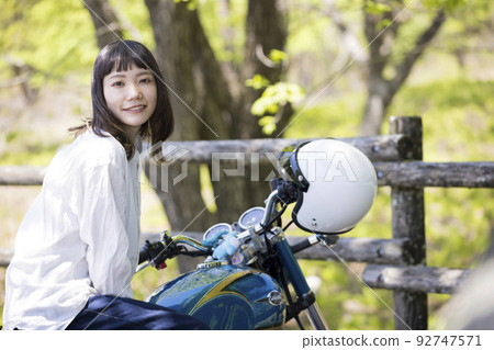 Bike girl image Young woman straddling a motorcycle 92747571