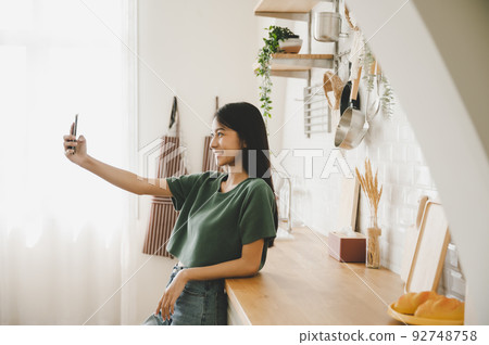 Pretty young asian female with big smile and stand at kitchen room Pretty young asian female with big smile and stand at kitchen room 92748758