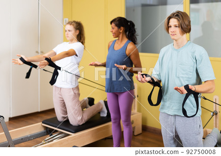 Teenagers training pilates in gym with trainer Teenagers training pilates in gym with trainer 92750008