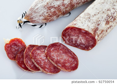 Spanish longaniza salami sausages cut in slices on a white surface 92750054