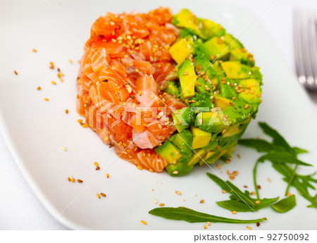 Salmon tartare with avocado served on plate with arugula 92750092