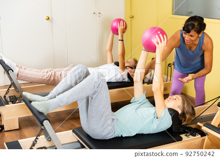 Teens doing pilates exercises with trainer 92750242