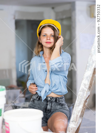 Sexy woman in denim shirt and shorts next to a stepladder in room being renovated 92750332