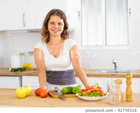 Young positive woman cooking salad on kitchen Young positive woman cooking salad on kitchen 92750528