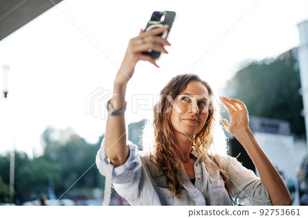 Young woman taking selfie on smartphone in the street 92753661